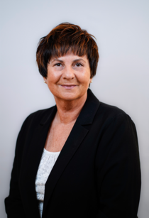 Porträtfoto einer Frau mit kurzem dunkelbraunem Haar im Blazer.